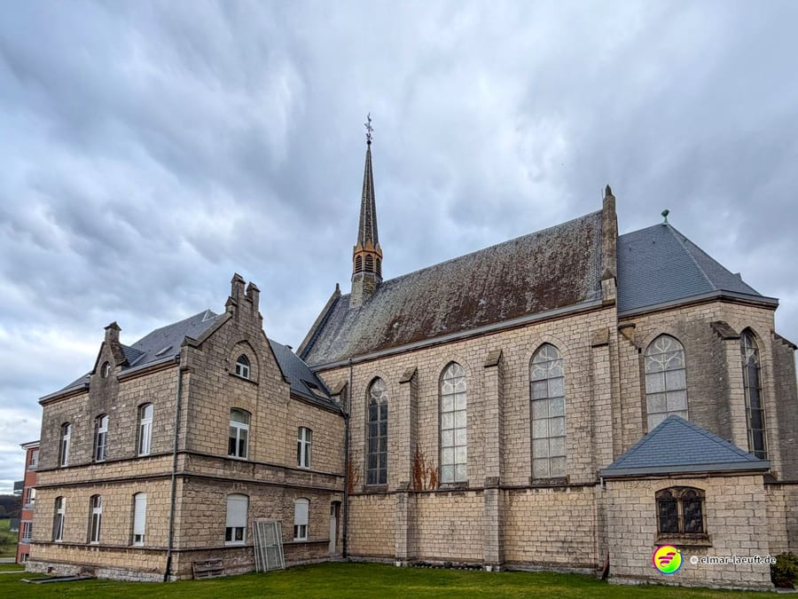 Großes neugotisches Kirchengebäude aus hellem Naturstein mit hohen Spitzbogenfenstern. Die imposante Kirche zeigt typische Merkmale des 19. Jahrhunderts mit Strebepfeilern und Satteldach.