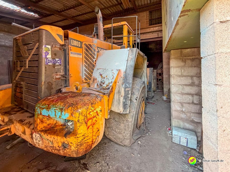 Laufabenteuer in Maasmechelen führt an einem verlassenen, verrosteten Baumaschinen-Giganten in einer alten Halle vorbei.